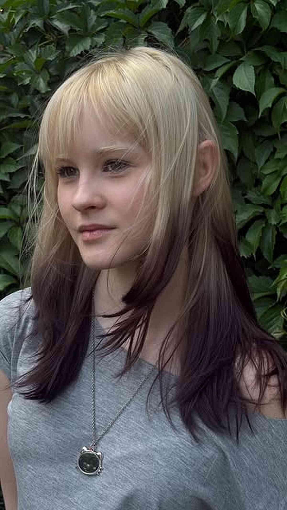 Layered blonde and dark plum hair below the shoulders with a wispy fringe.