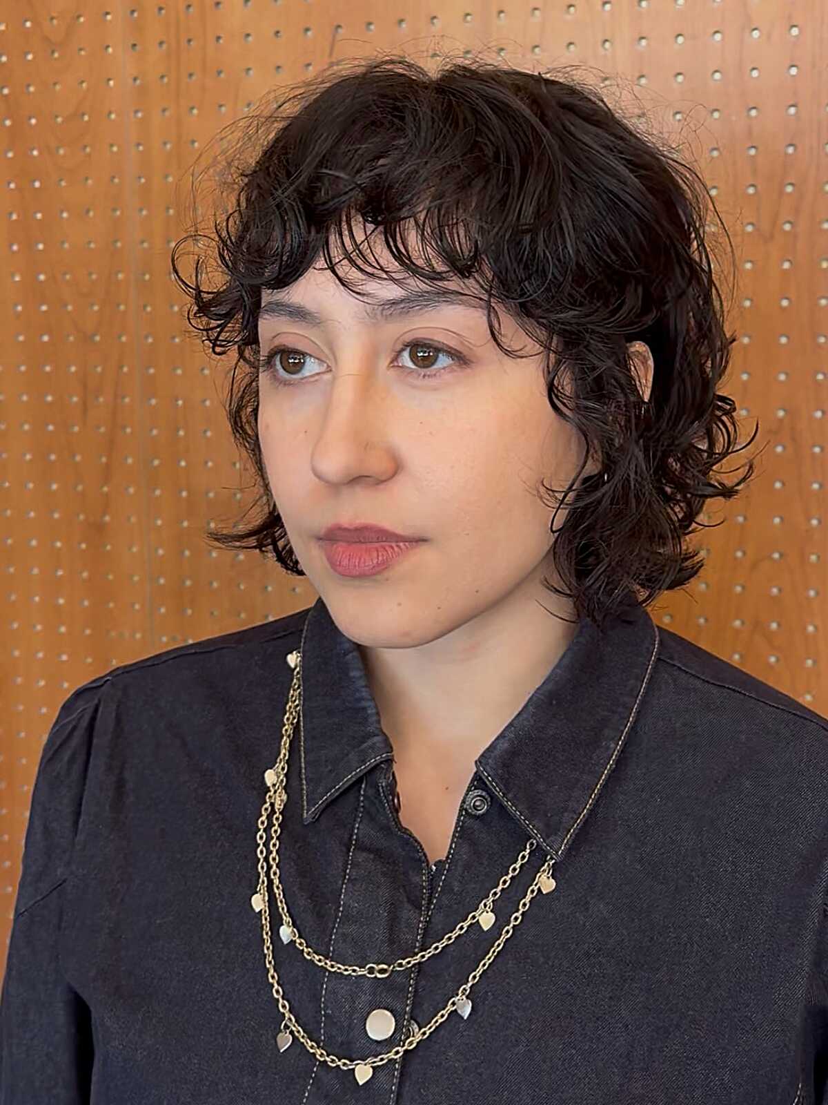 Short curly dark bob with a textured fringe and airy shape.