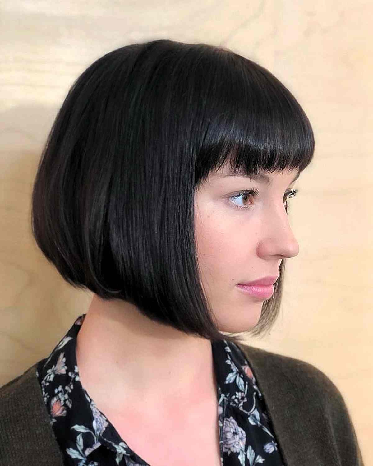 Black angled bob with straight bangs and a smooth rounded shape.