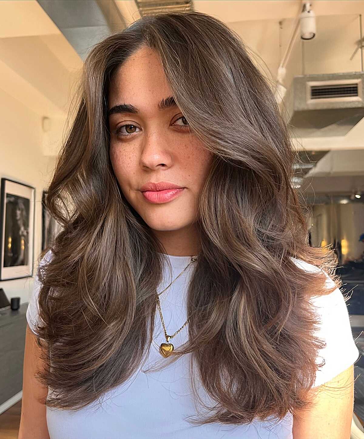 Long medium brown hair with curtain layers and soft bounce.