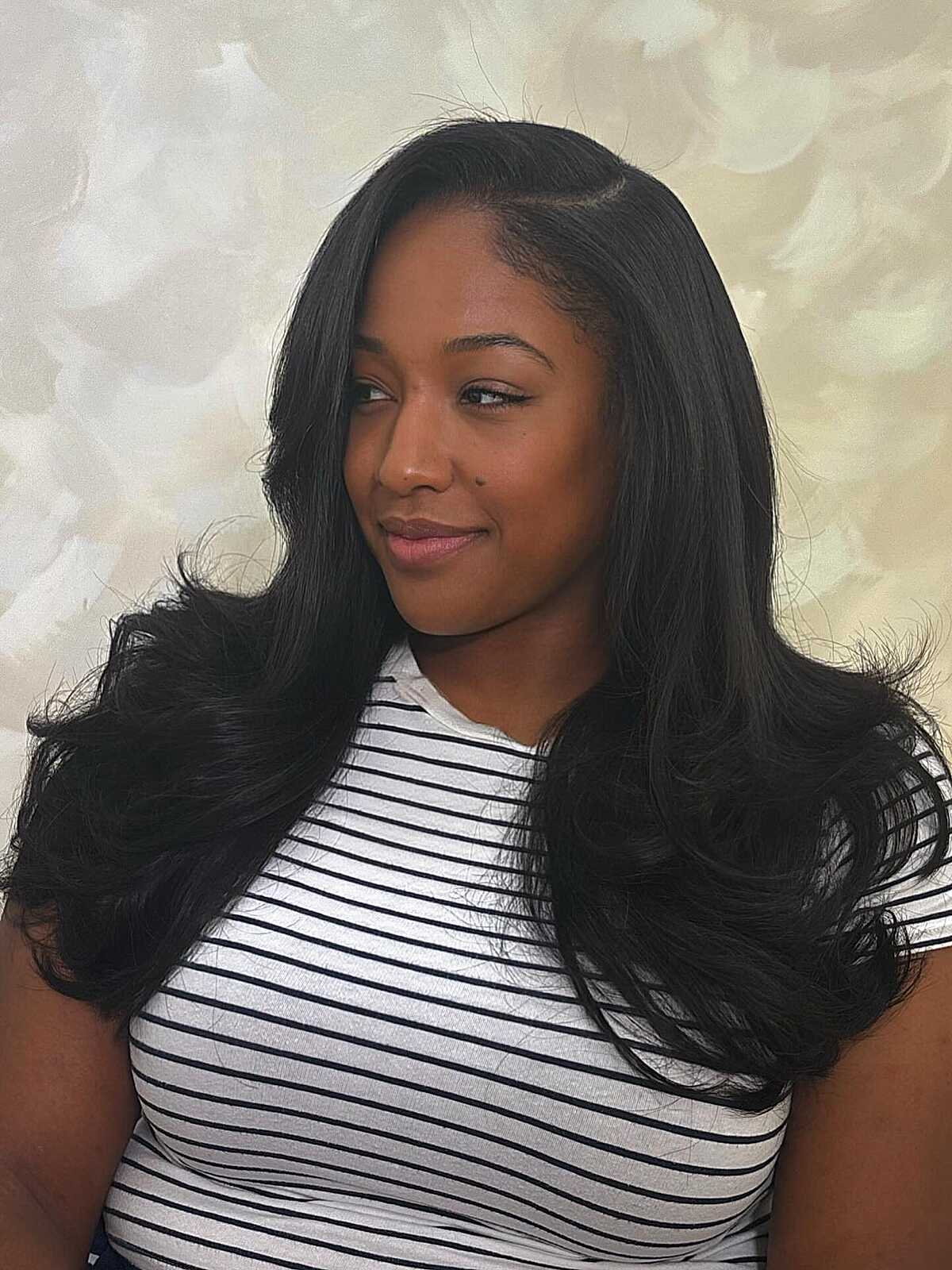 Long jet black hair with flipped layered ends and a side part.