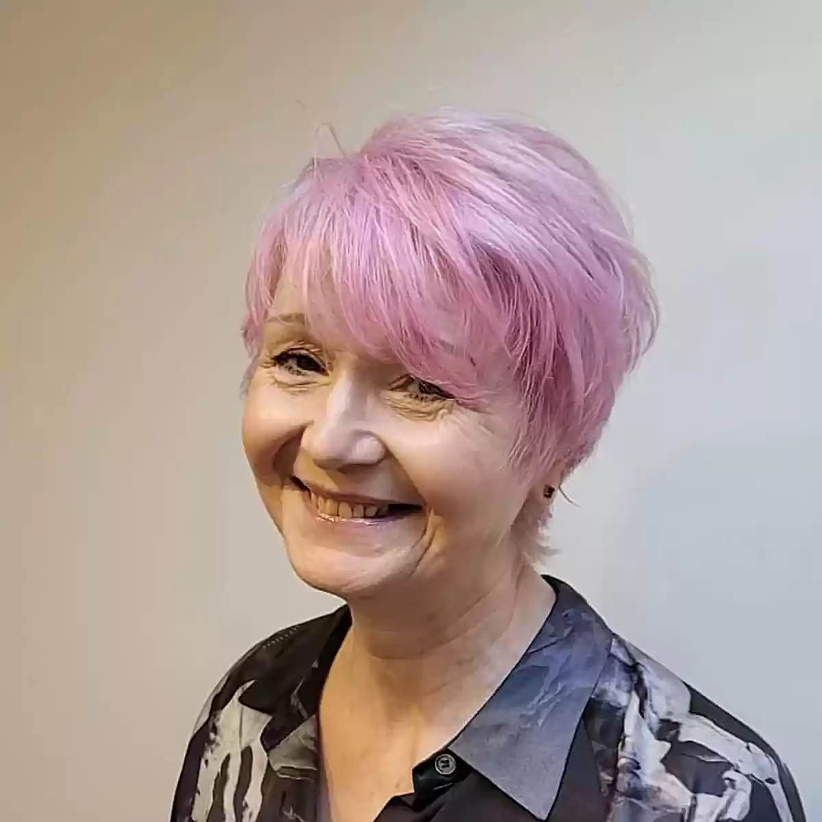 Pastel pink pixie bob with wispy layers and short fringe.