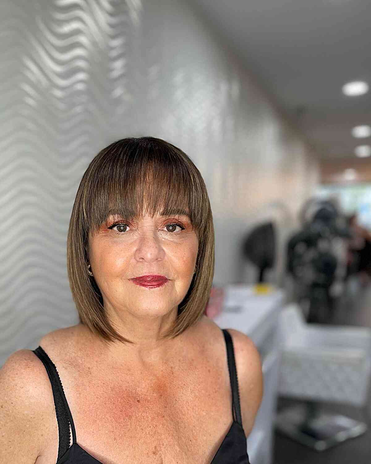 Chin-length bob with blunt bangs and smooth ends.