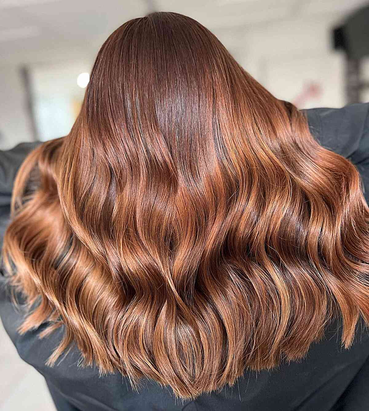 Long wavy copper bronde hair with warm reflective color.