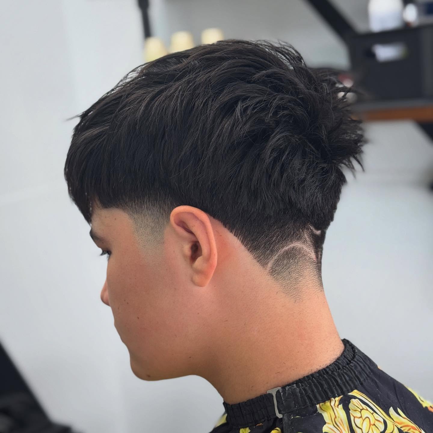 Textured top with taper fade and shaved nape design.