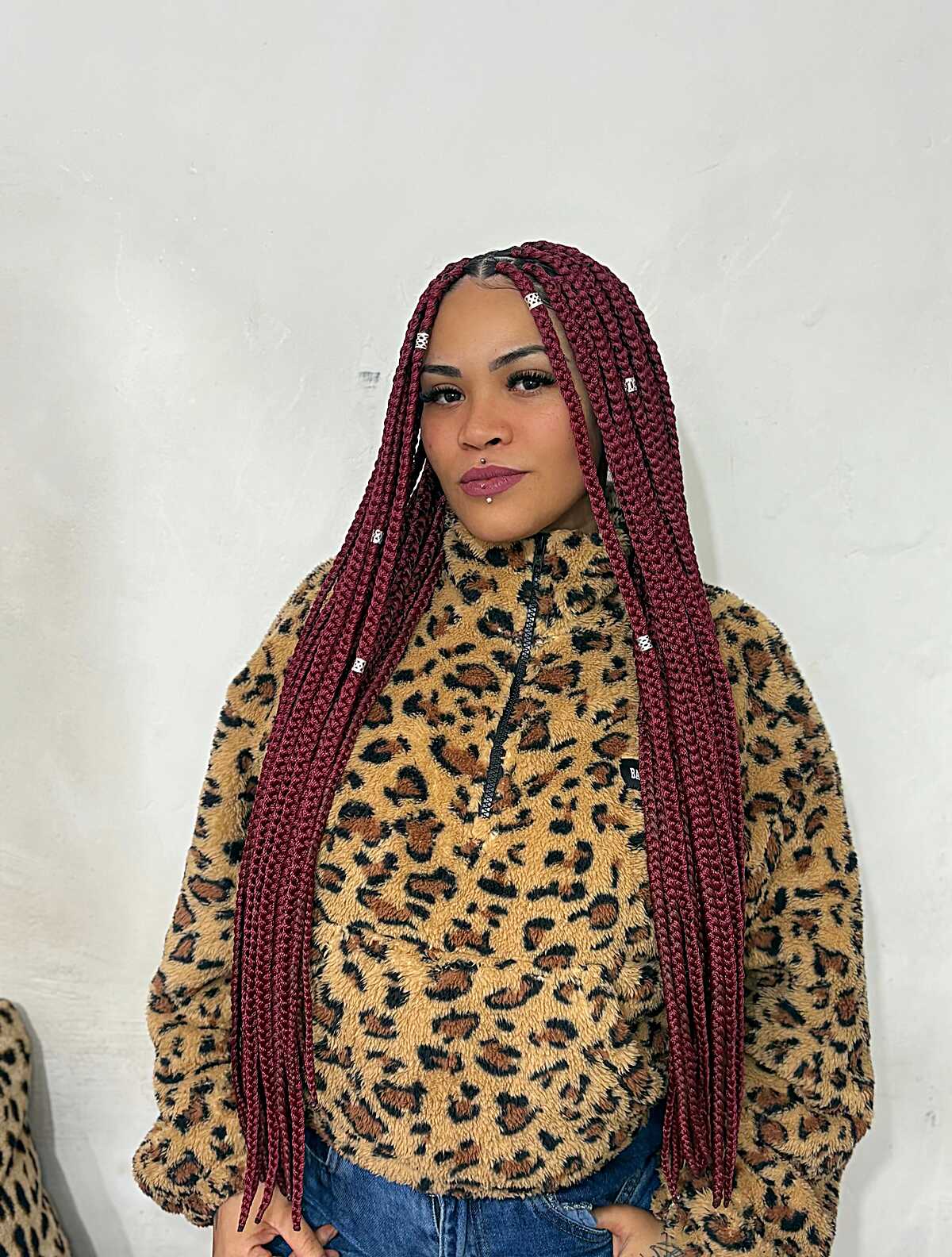 Long burgundy box braids with silver cuffs and a center part.