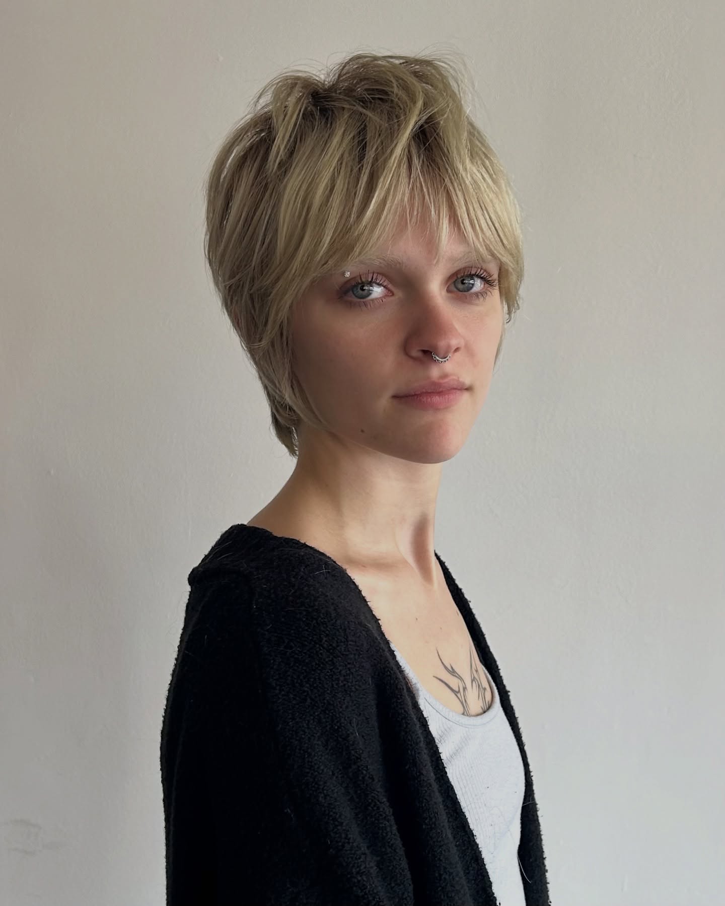 Ash blonde shaggy pixie with feathered fringe and tapered back.