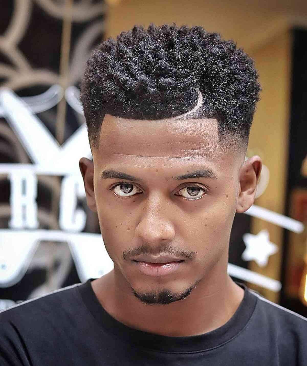 High textured curls with a faded side and curved design line.