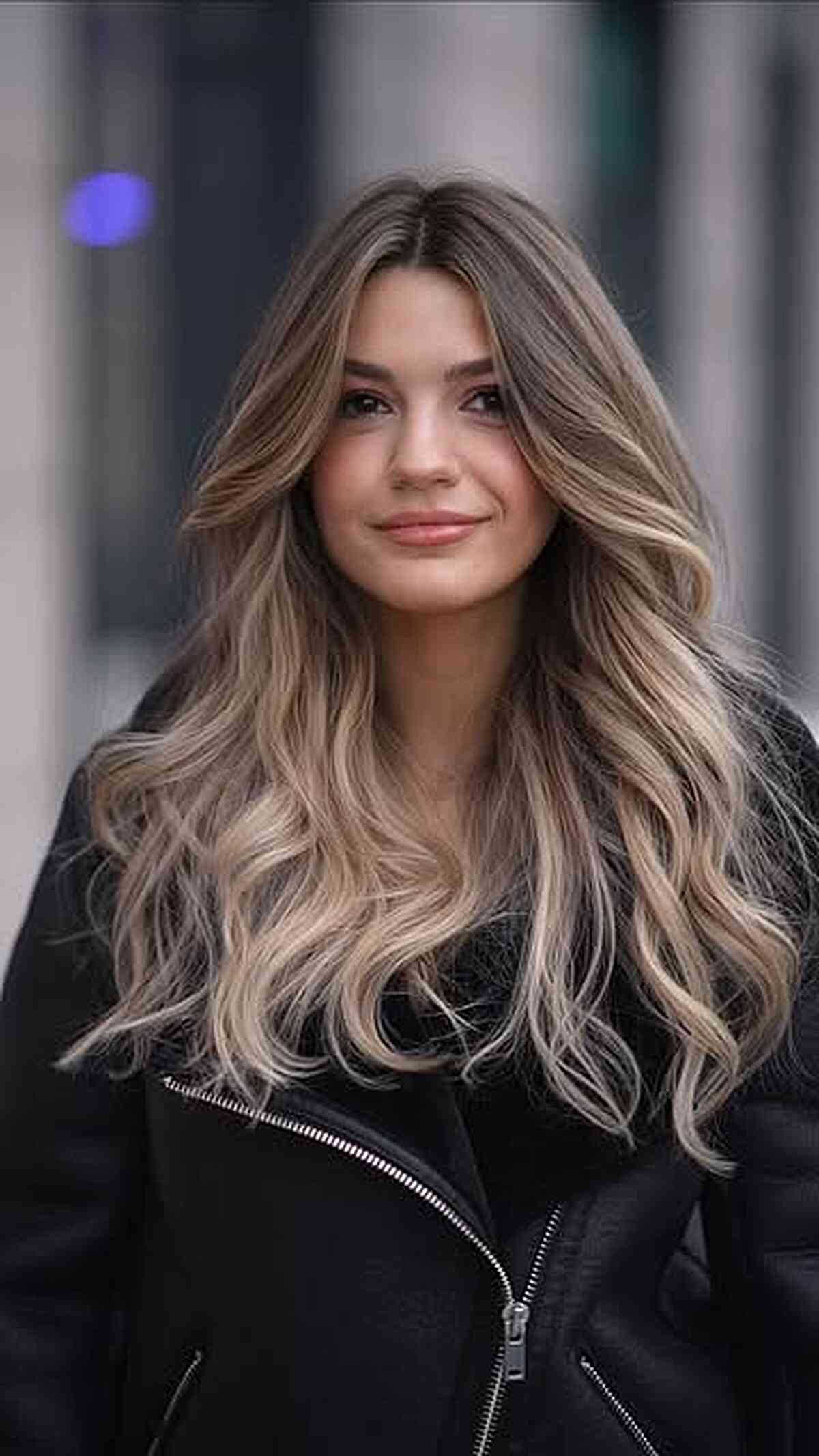 Long bronde balayage with soft loose waves and a center part.