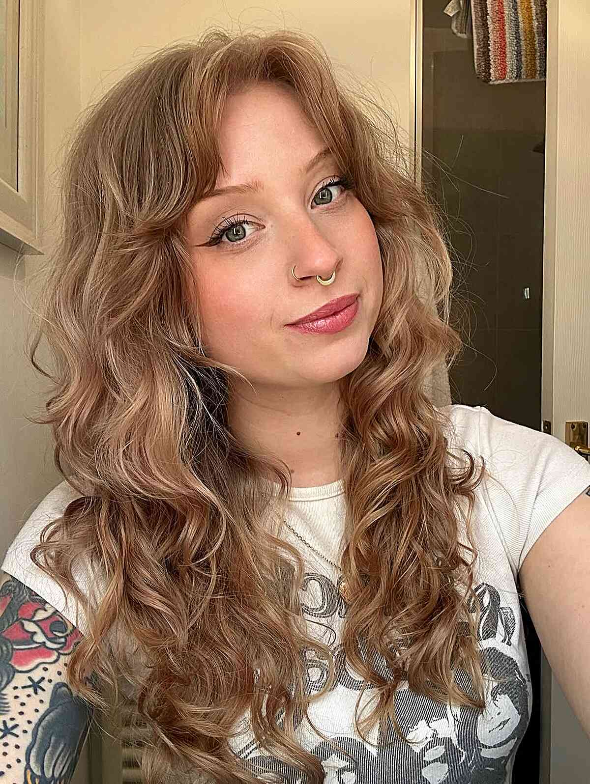 Long wavy hair with curtain bangs and soft volume.