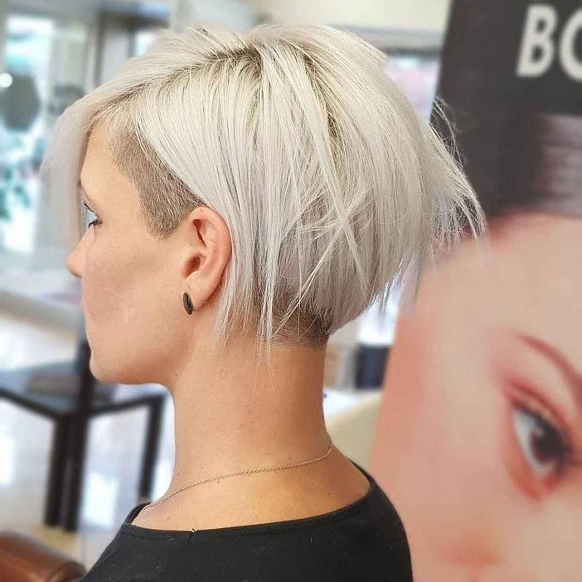 Platinum pixie bob with a shaved side and airy top layers.