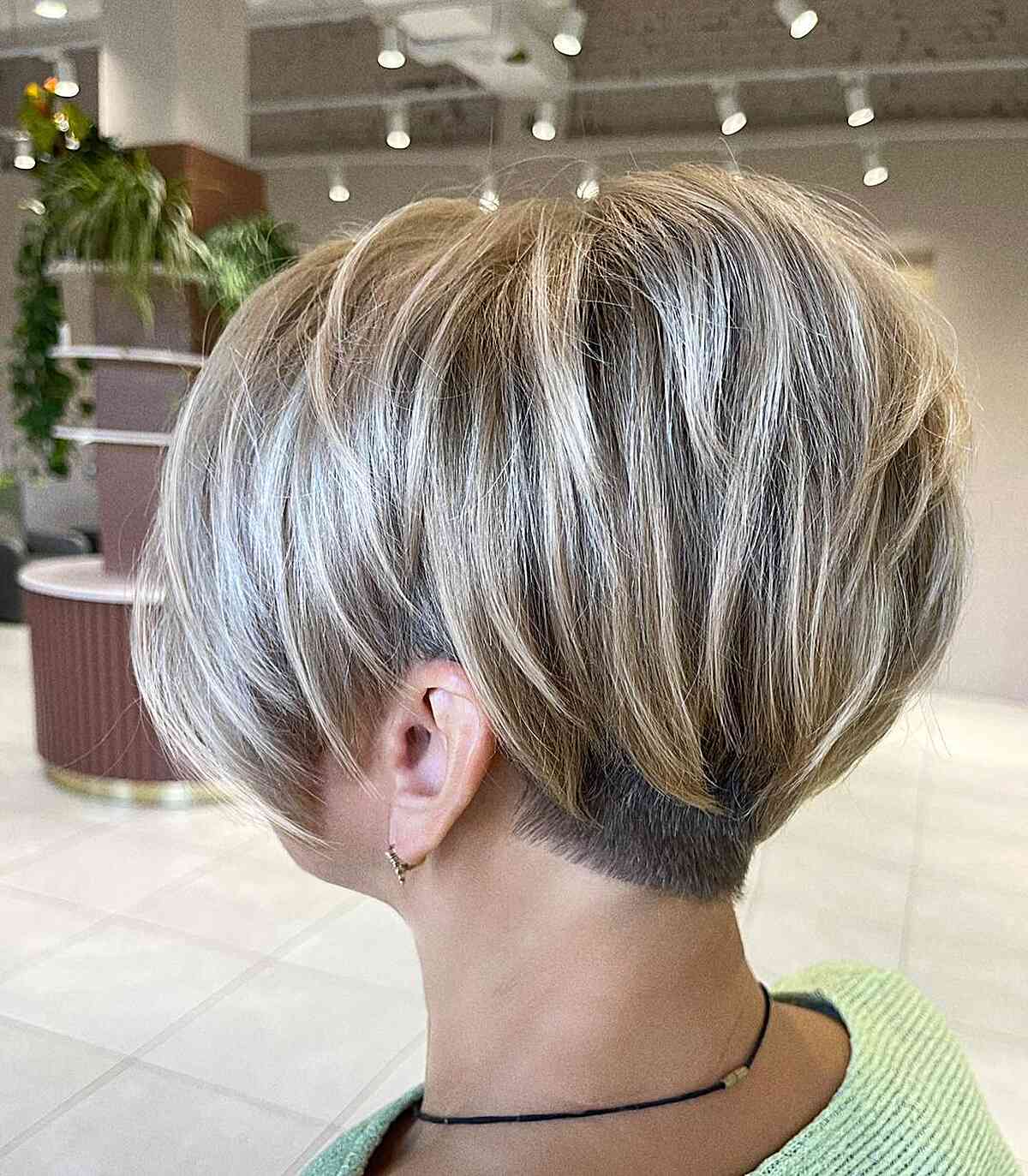 Soft curved pixie bob with layered blonde top and short nape.