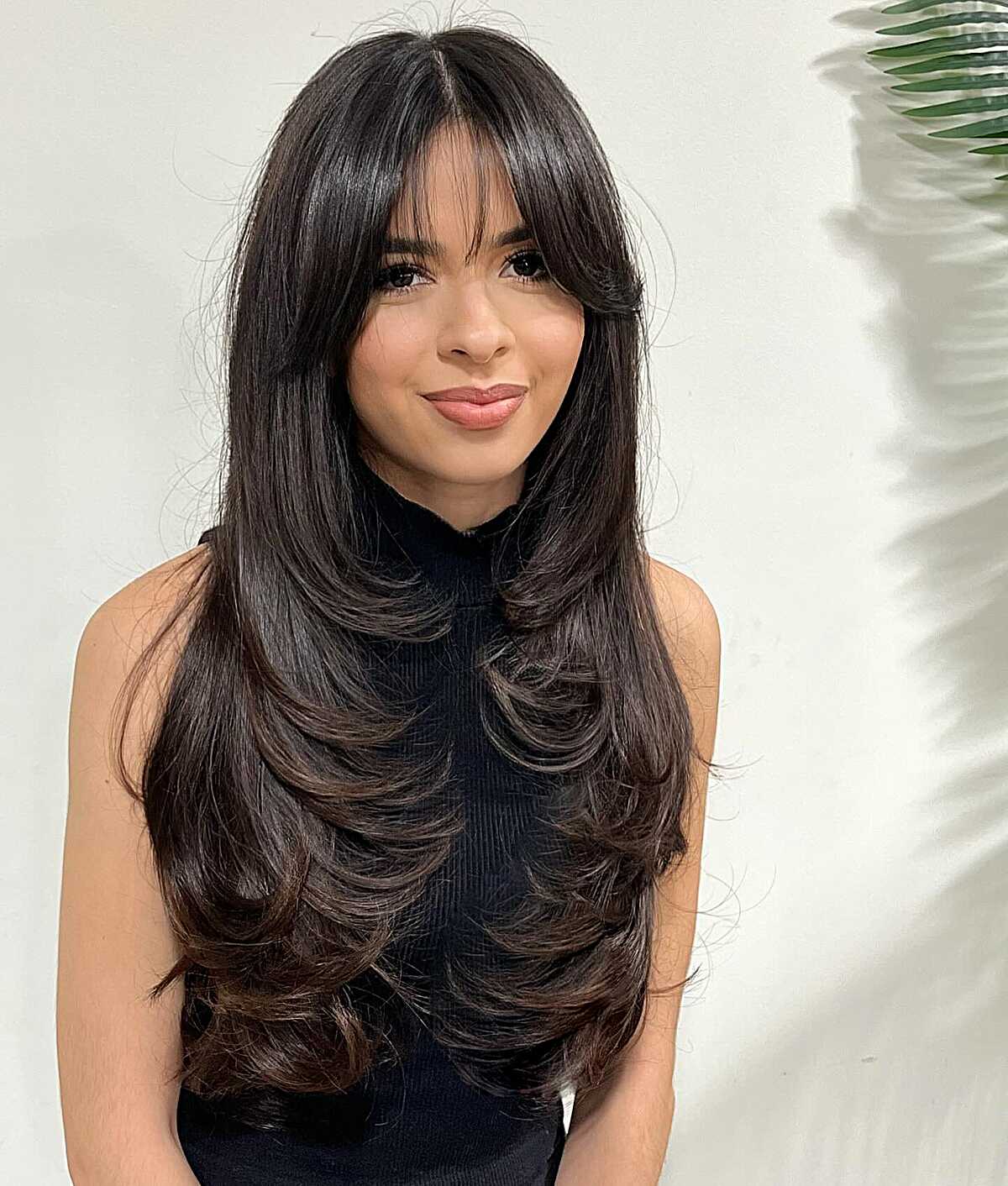 Long dark hair with curtain bangs and layered curled ends.