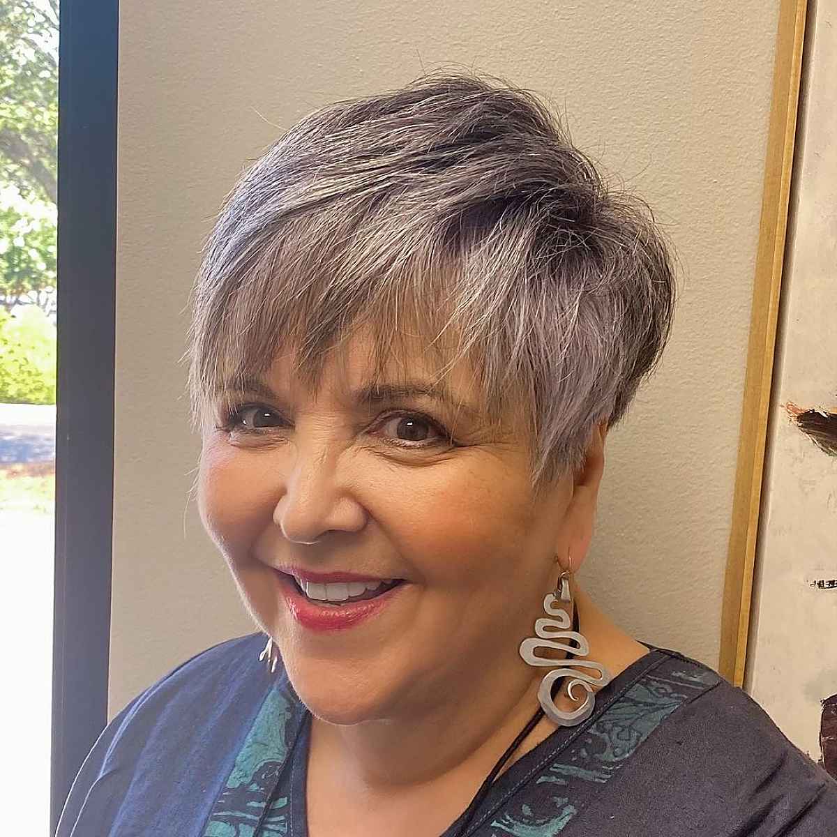 Salt-and-pepper cropped pixie with soft fringe and rounded shape.