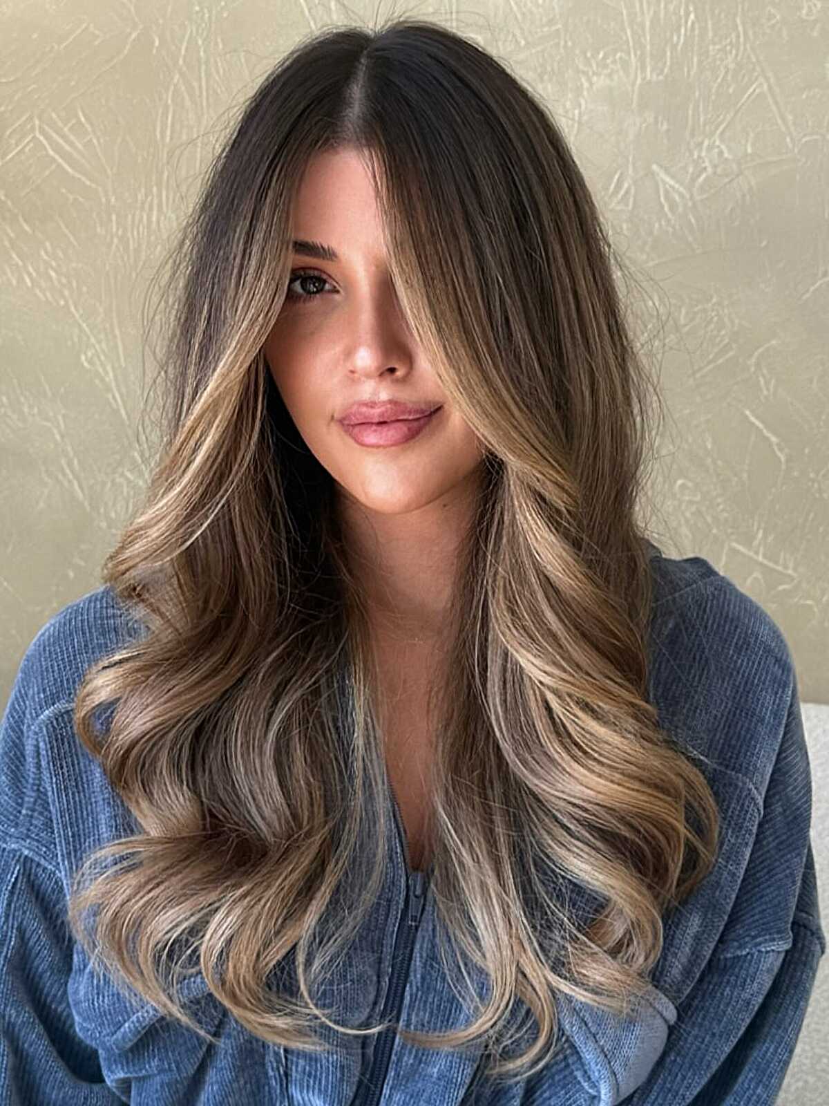 Long bronde waves with dark roots and bouncy curled ends.