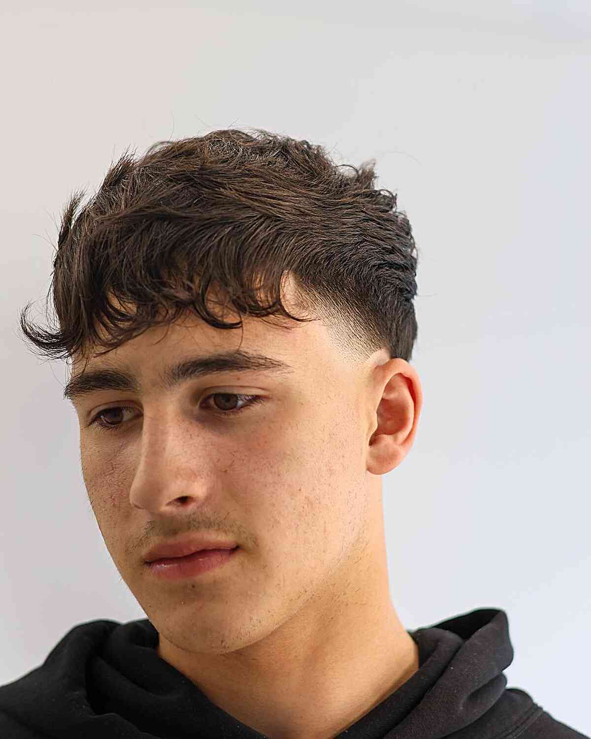 Short textured fringe with a clean temple fade and tight sides.
