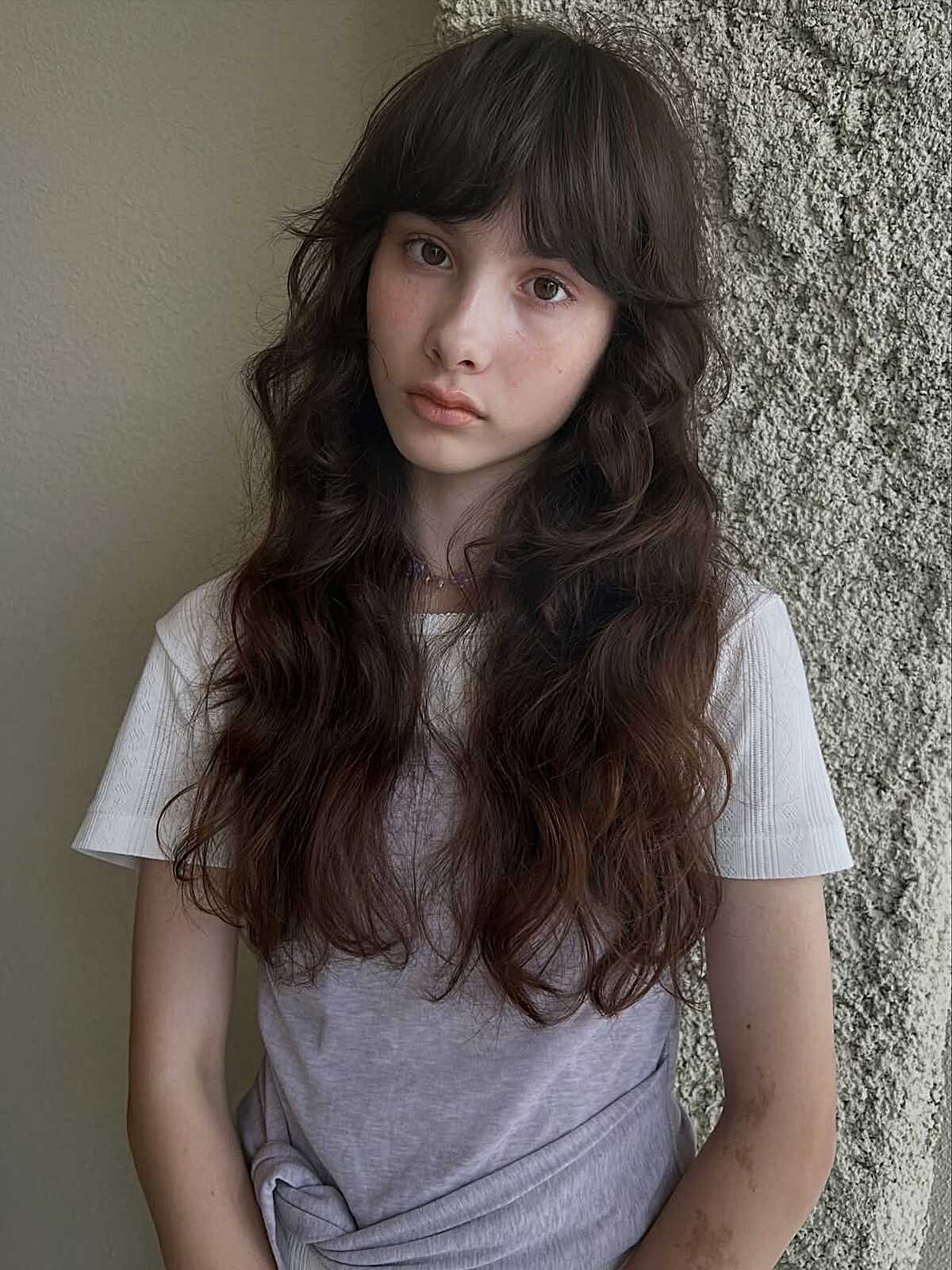 Long dark brunette waves with full soft bangs.
