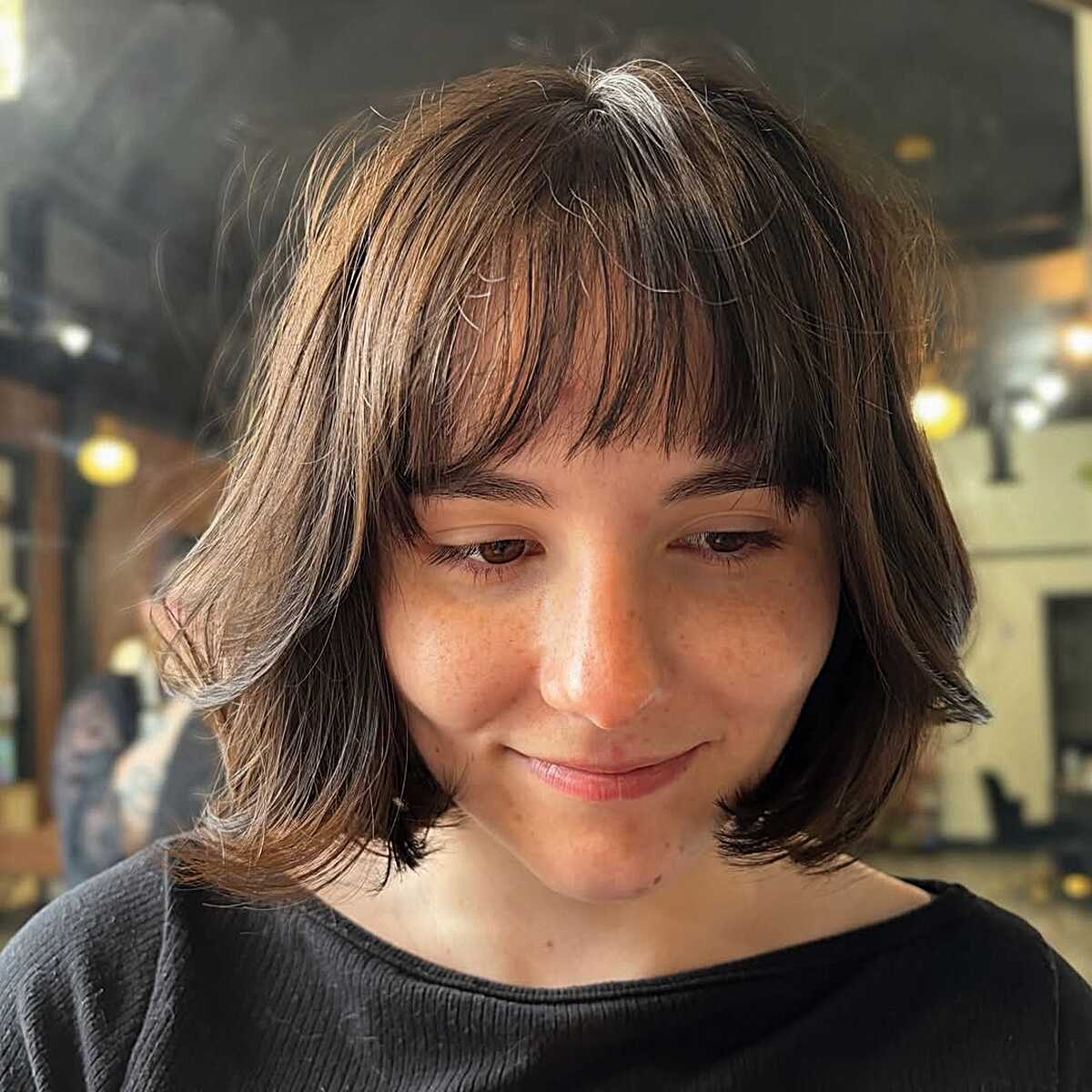 Brunette chin-length bob with shaggy bangs and soft layers
