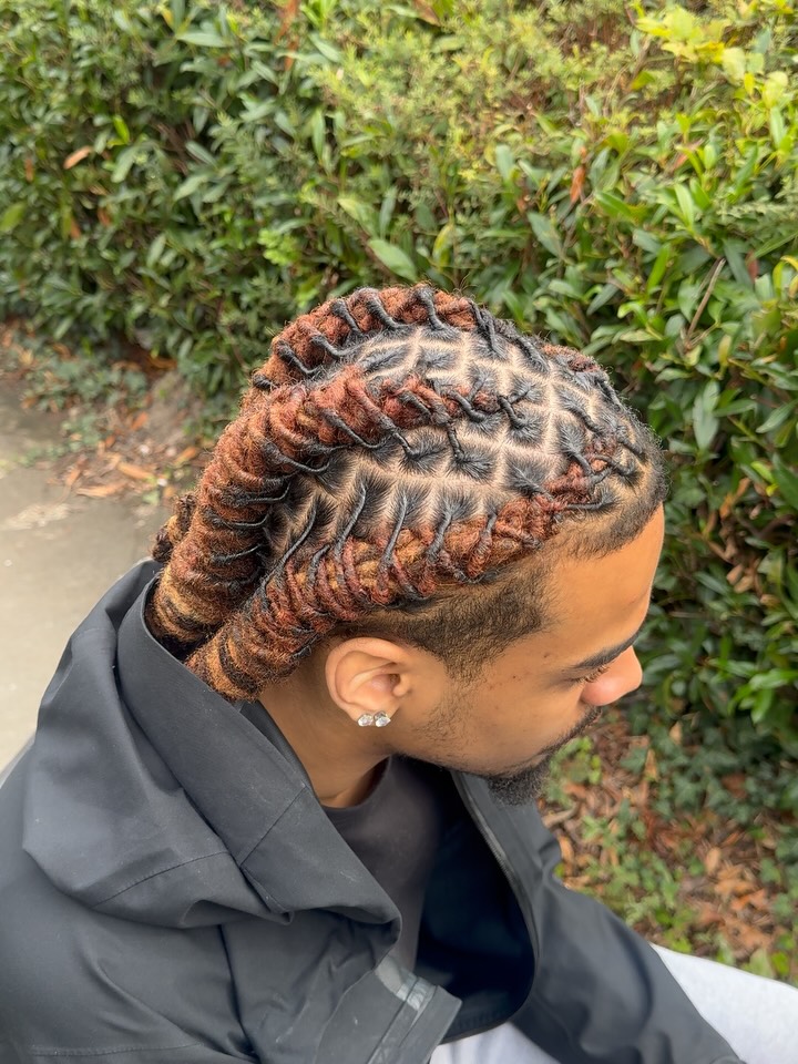 Swept-back dread twists with copper-toned color through the lengths.