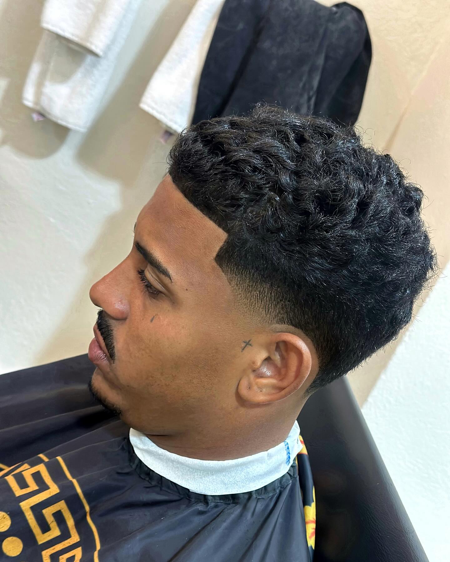 Defined curls on top with a gradual taper fade.