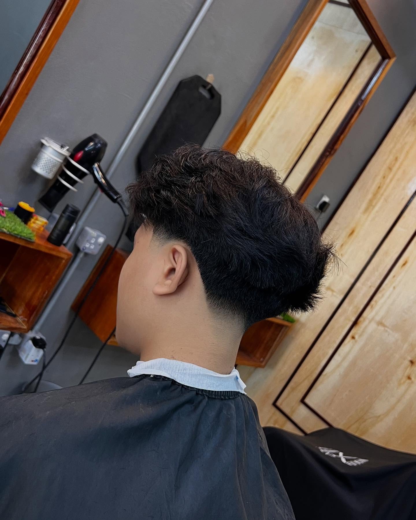 Curly top with tapered back and short sides.