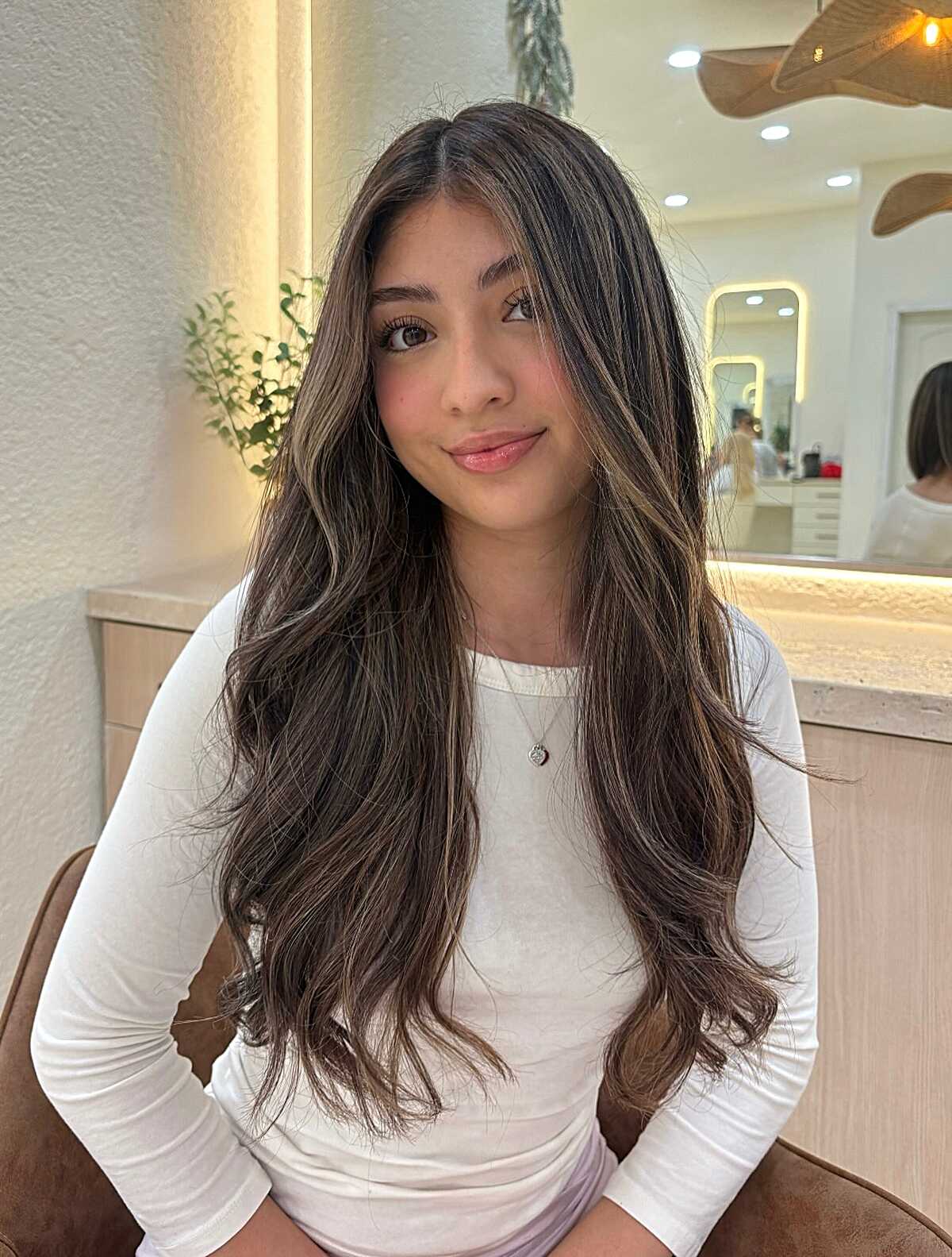 Long dark brown layered hair with soft subtle lowlights.