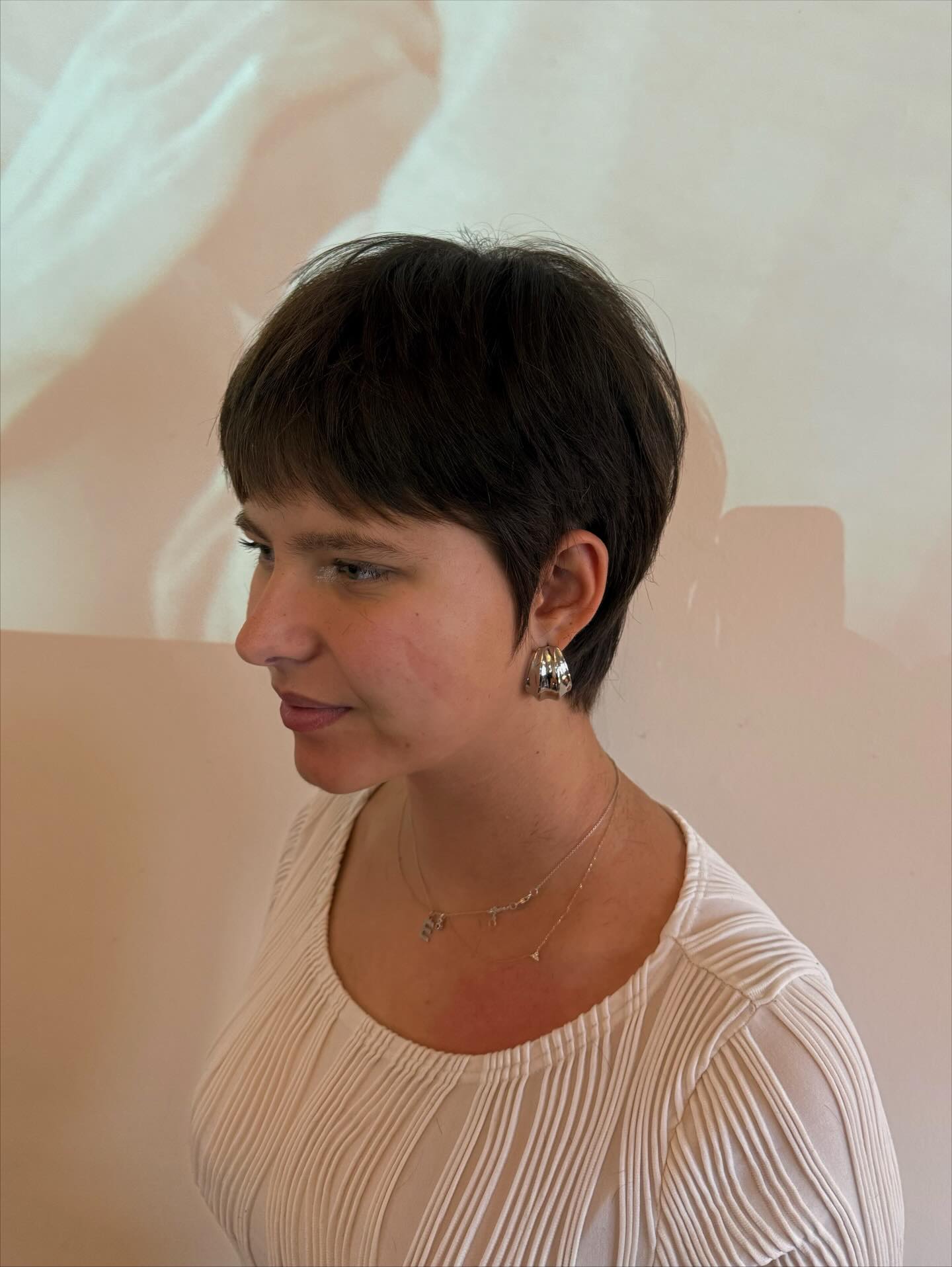 Dark short pixie with micro fringe and tapered nape.
