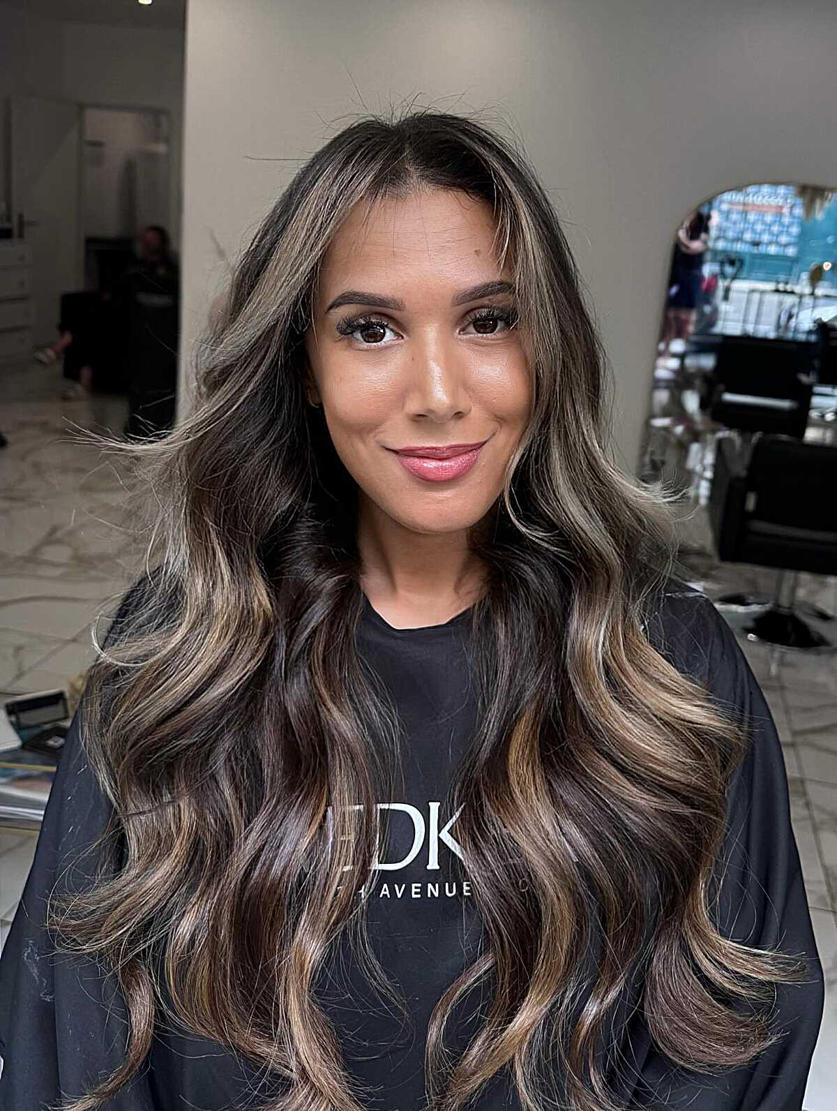 Long brunette waves with blonde money pieces and dimensional color.