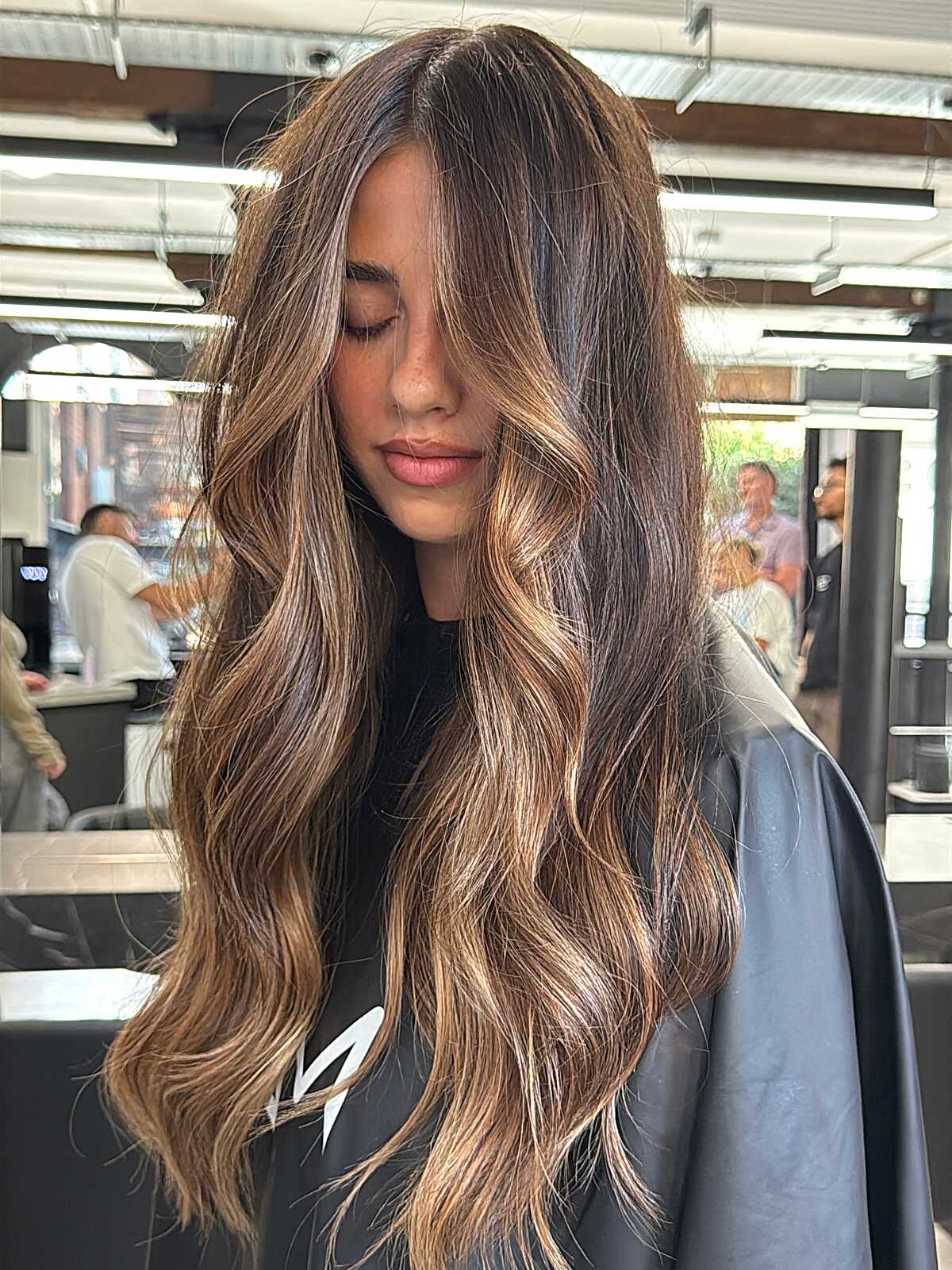 Long wavy dark brown hair with caramel ribbons.