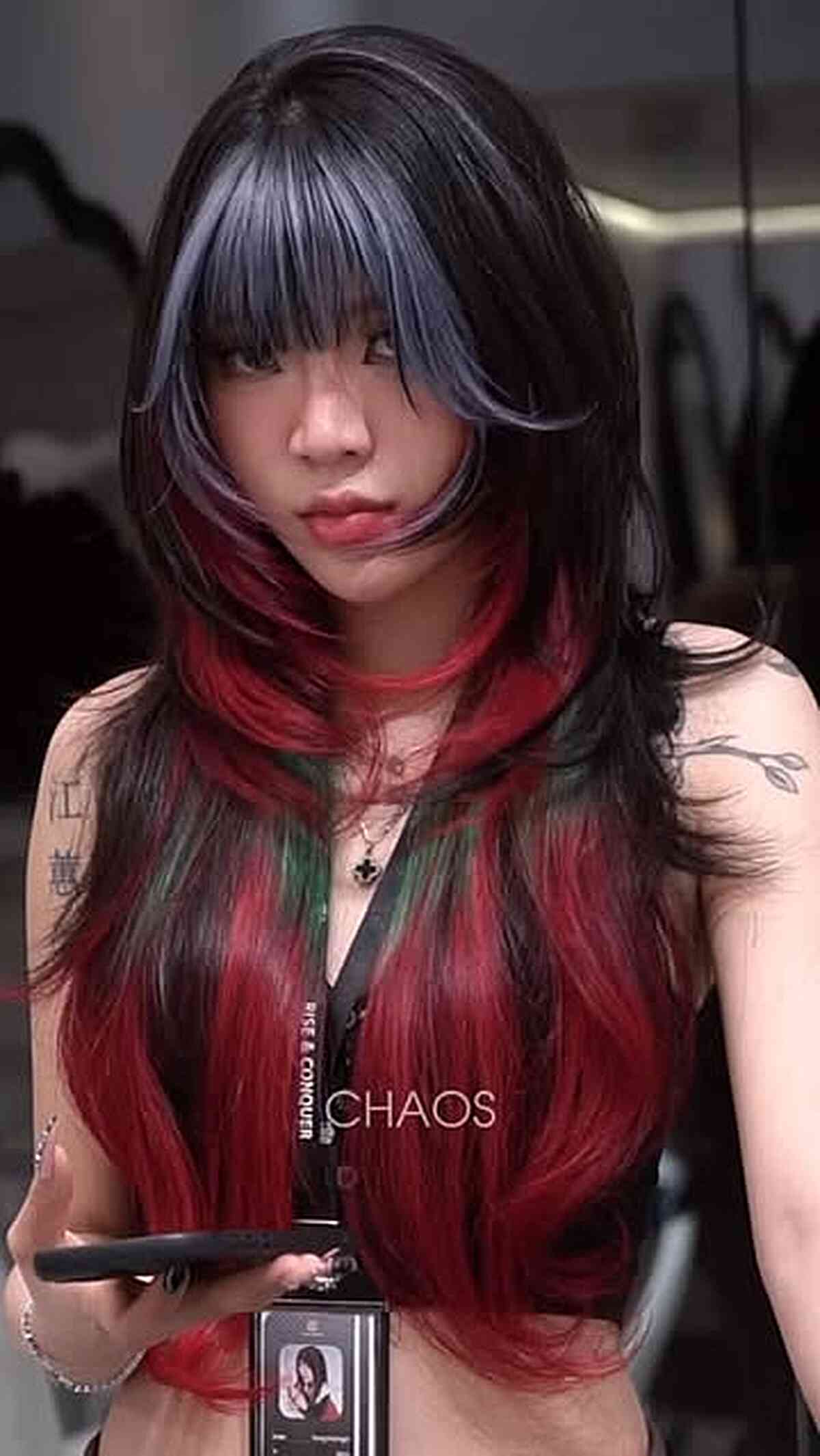 Long layered shag with blunt bangs, black top, and vivid red lower lengths.