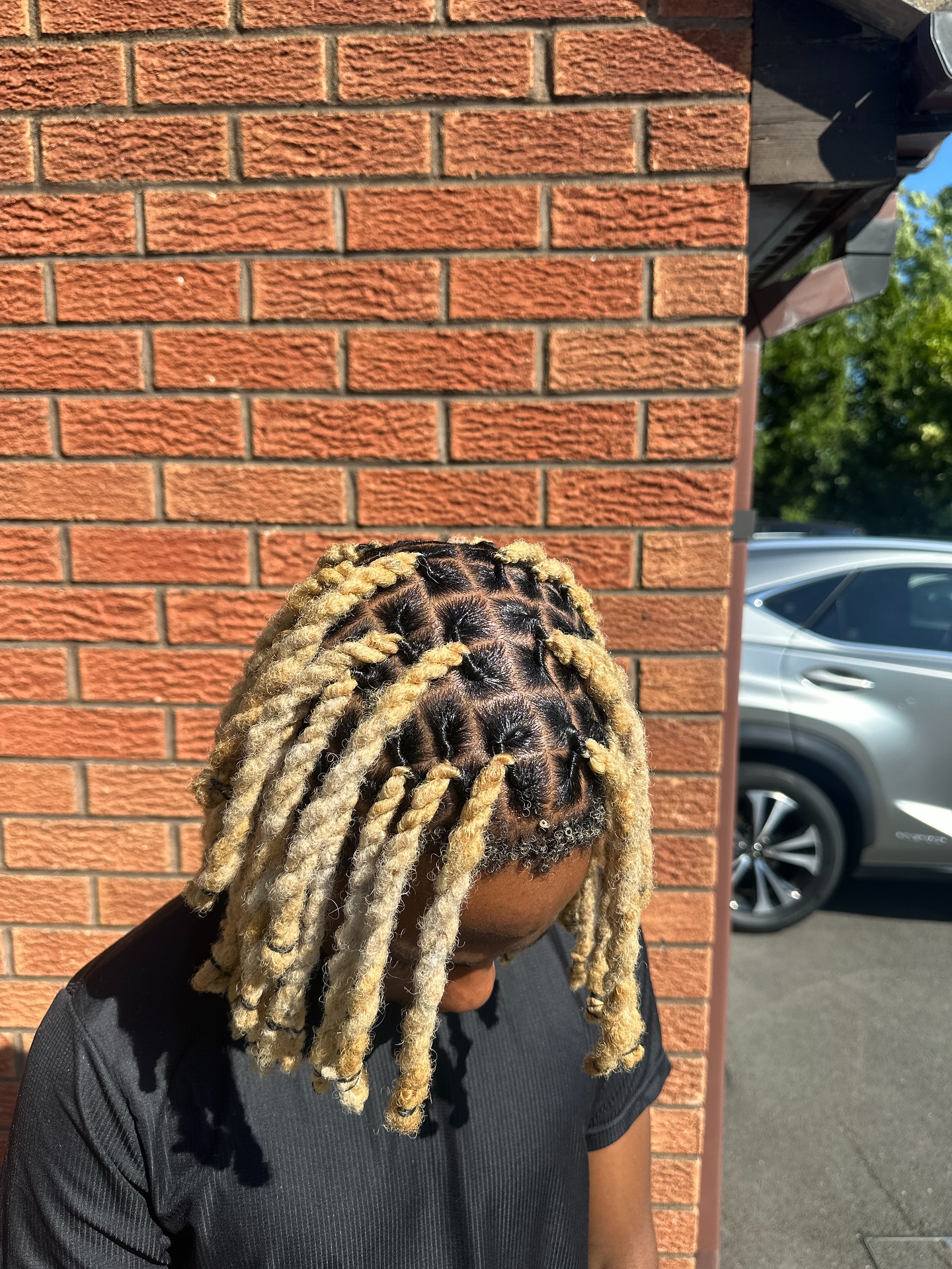Shoulder-length dreadlocks with blond ends and dark roots.