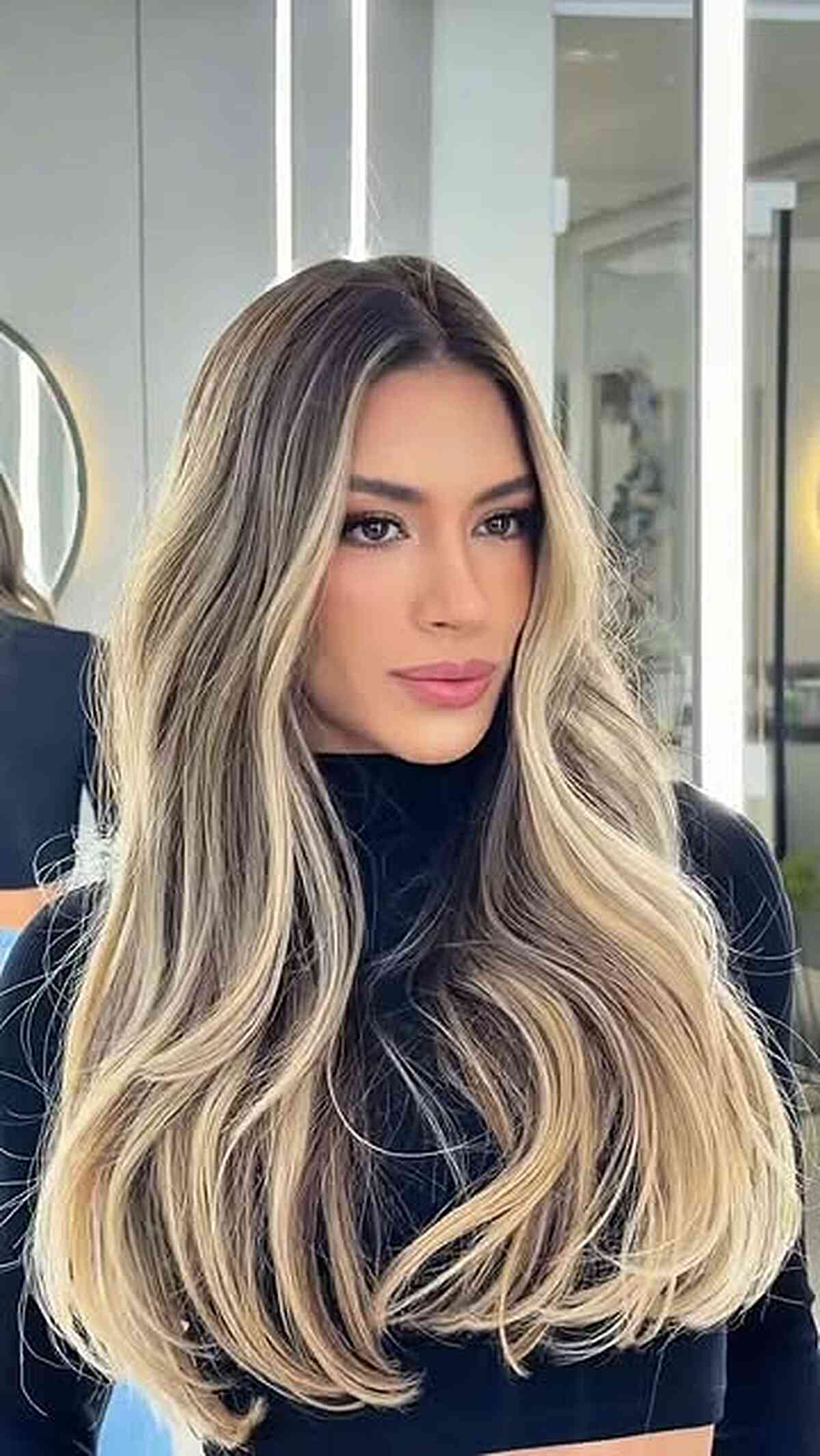 Long beige blonde layers with smoky roots and waves.