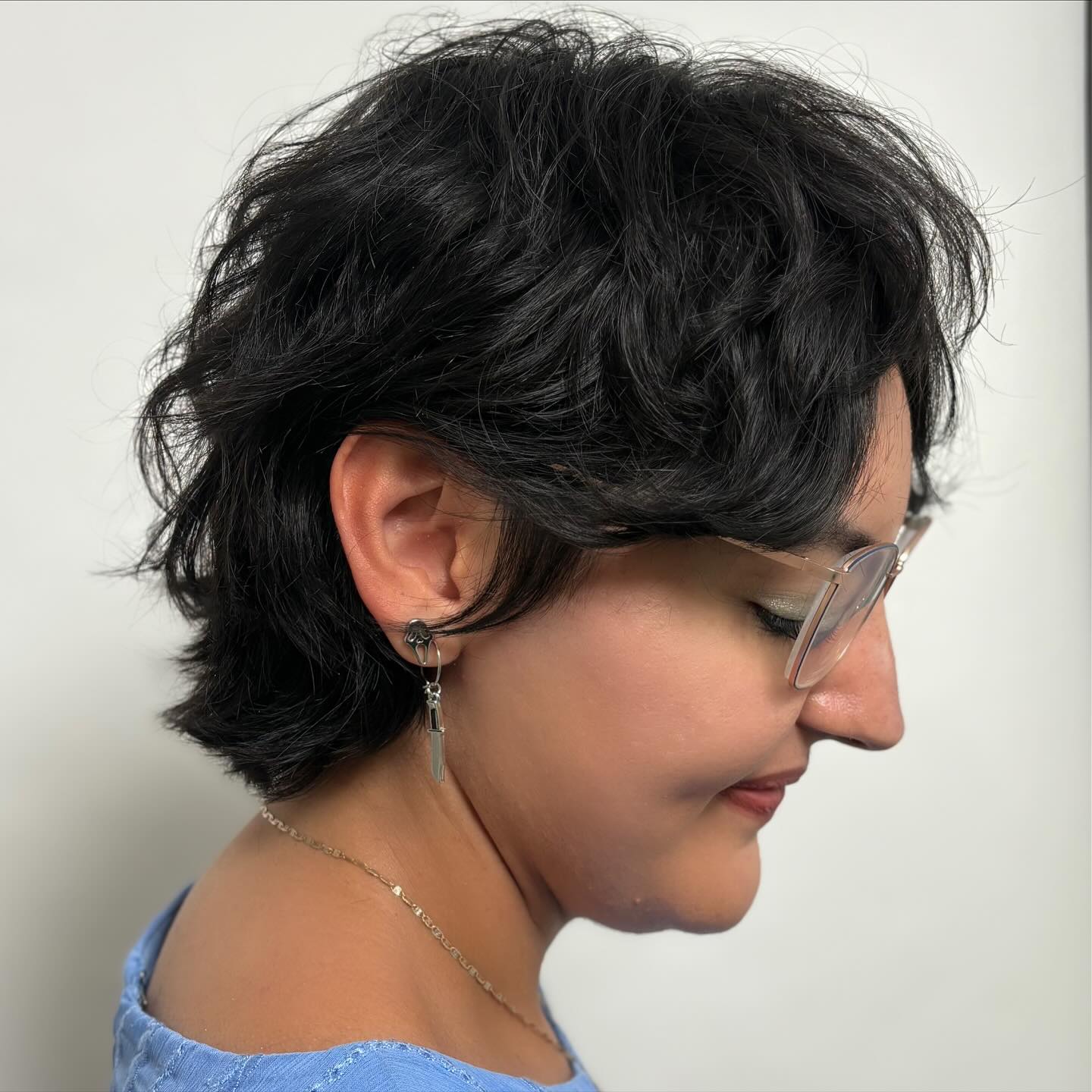 Tousled black pixie with soft fringe and flipped nape.