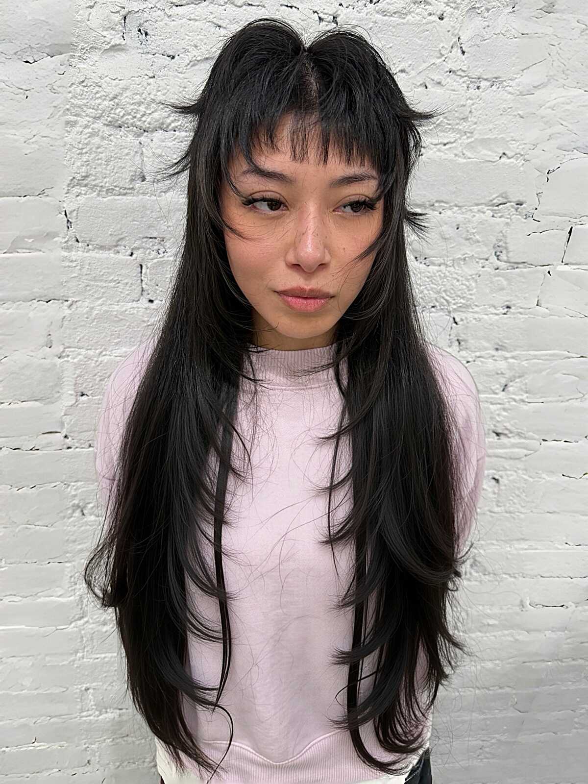 Long black hair with short face-framing pieces and wispy bangs.