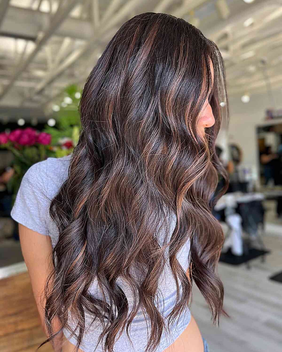 Long dark wavy hair with subtle light streaks.