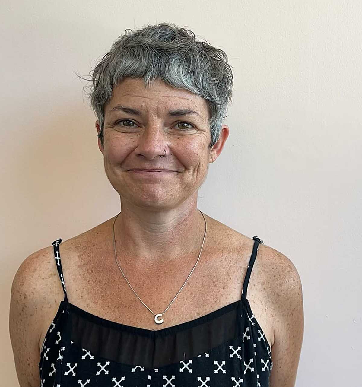 Salt-and-pepper pixie with natural curl and short fringe.
