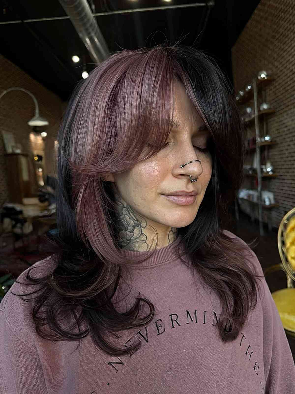 Long dark hair with smoky rose face-framing layers and curved ends.
