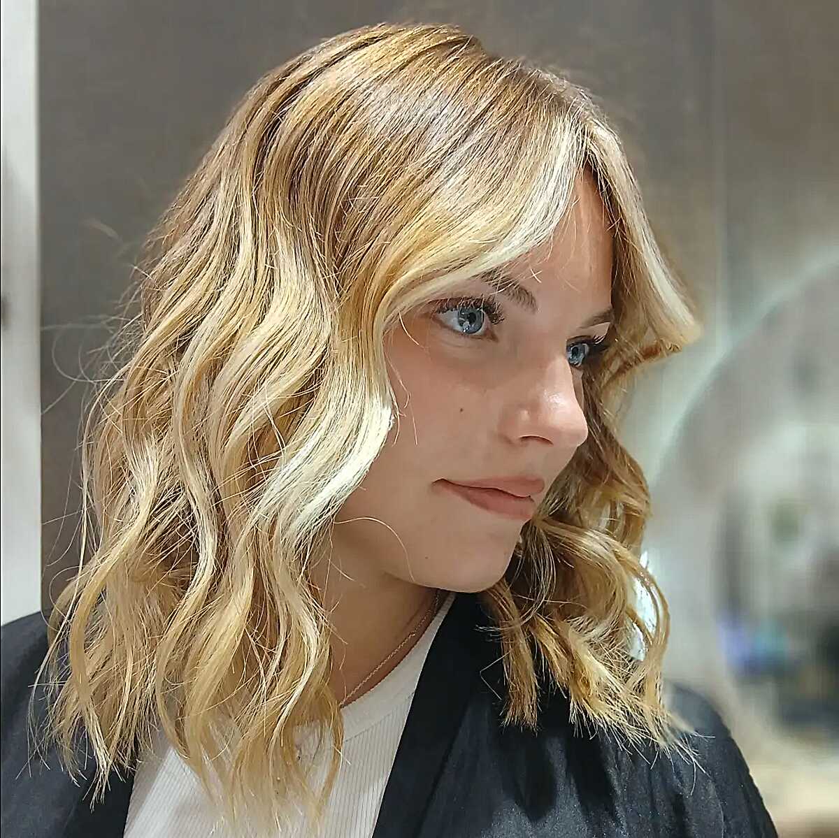 Golden blonde wavy lob with curtain fringe and soft texture.