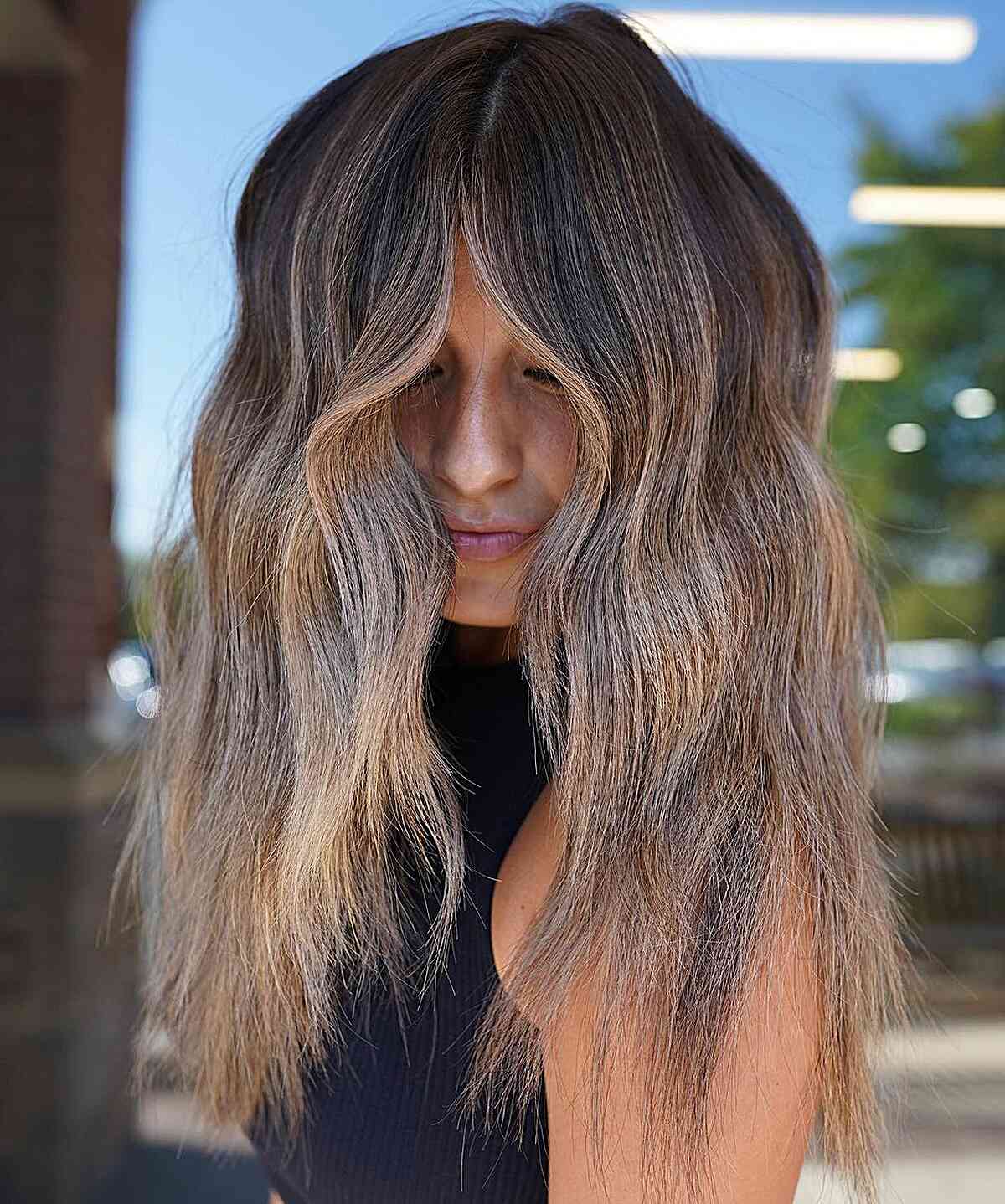 Very long bronde balayage with soft blended waves and wispy ends.