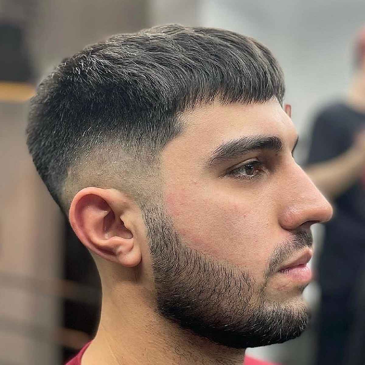 Short fringe haircut with a low fade and neat sides.