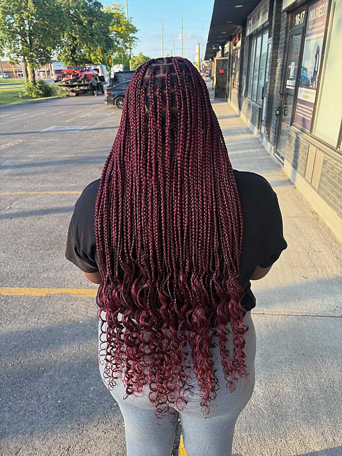 Waist-length burgundy braids with curled ends