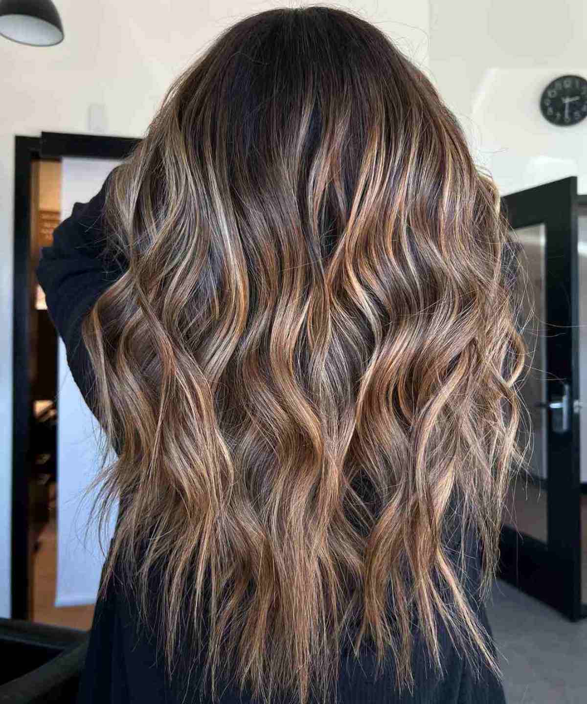 Long beachy bronde waves with dimensional caramel and beige highlights.