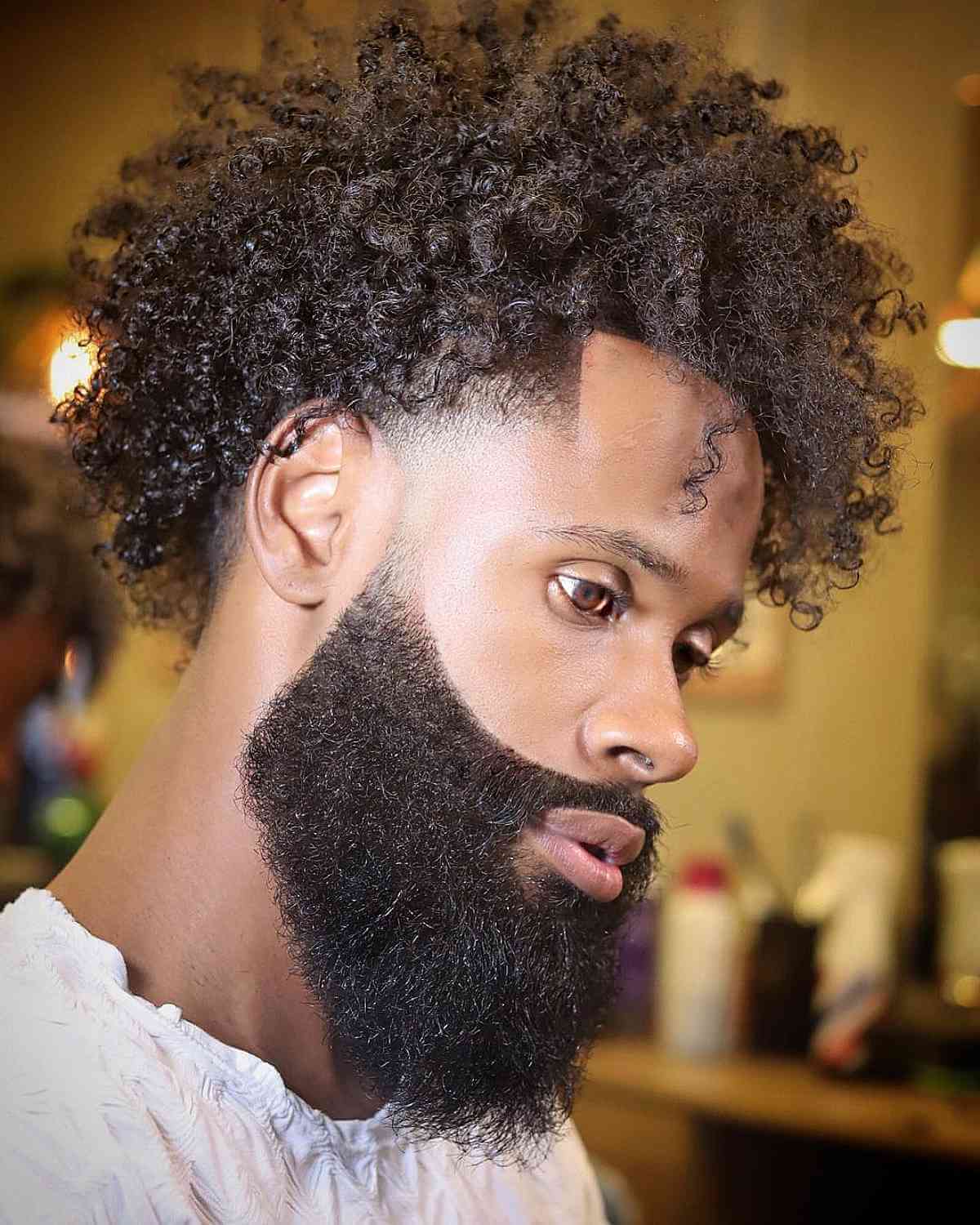 Curly frohawk with faded sides and a long pointed beard.