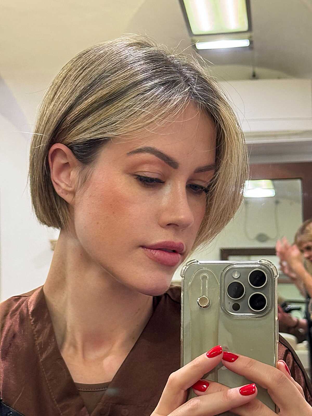 Ash blonde micro bob with a dark root shadow and clean jawline shape.