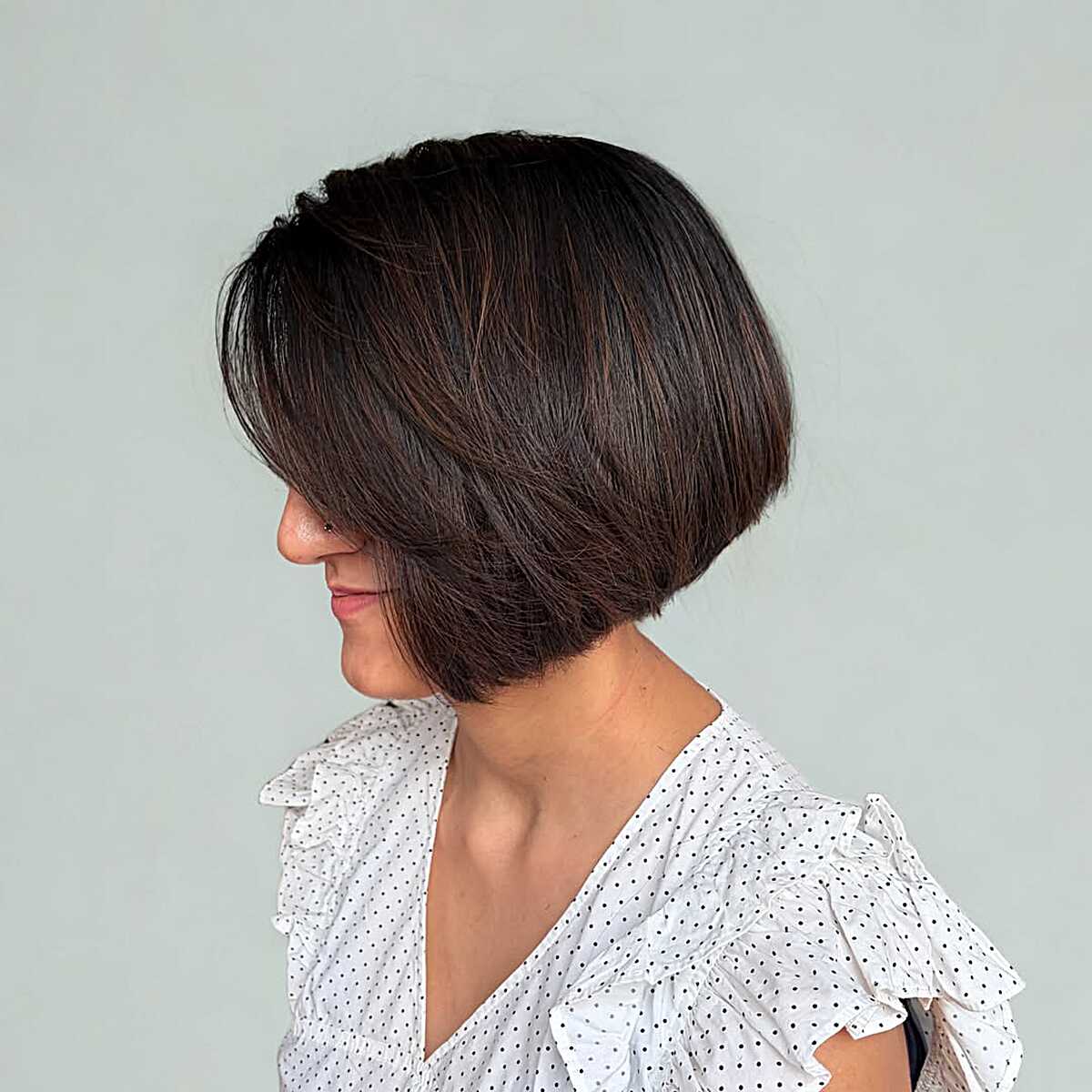 Chocolate brown angled bob with wispy ends and soft texture.