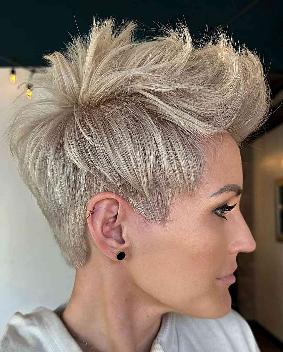 Platinum pixie with spiky top and closely cropped sides.