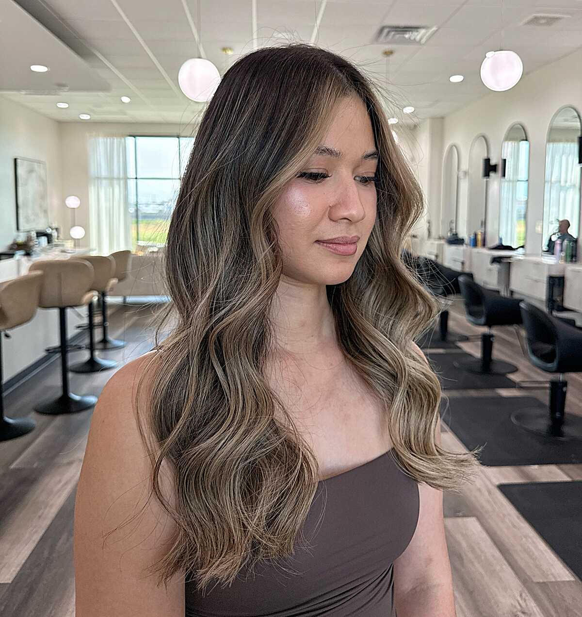 Long bronde balayage with warm face-framing pieces and waves.