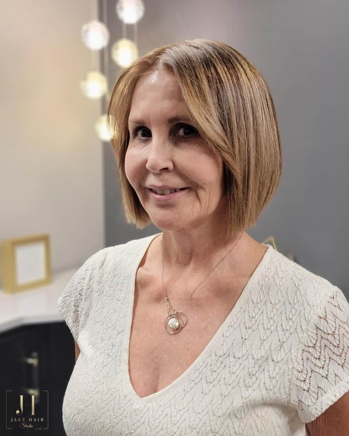 Short beige blonde bob with a center part and neat ends.