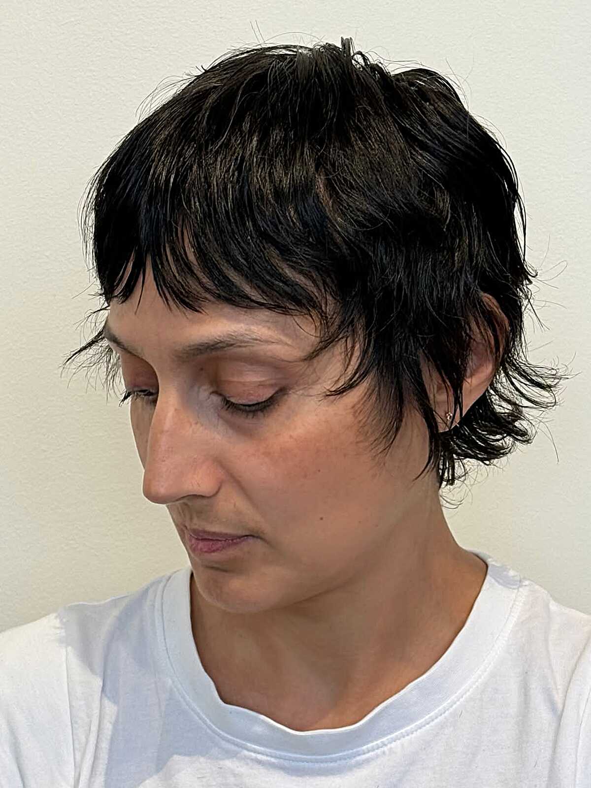 Dark shaggy pixie with choppy fringe and longer ear pieces.