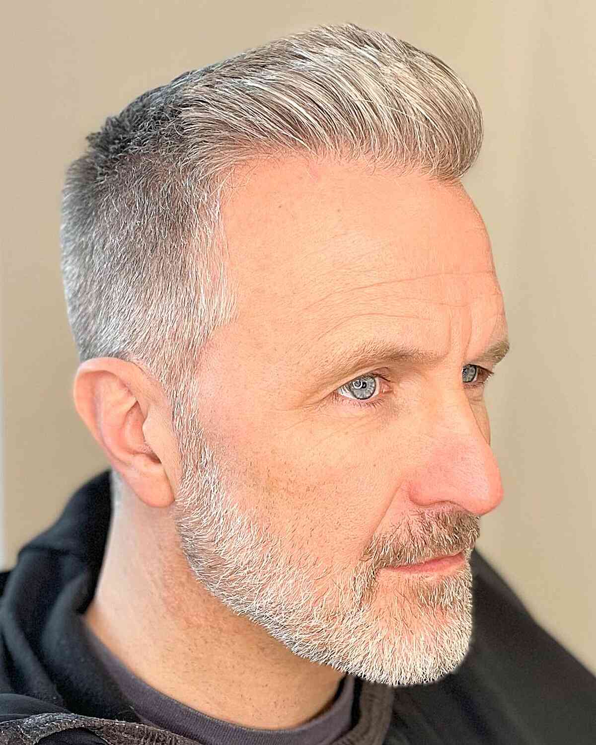 Short pompadour-style top with skin fade and gray hair.